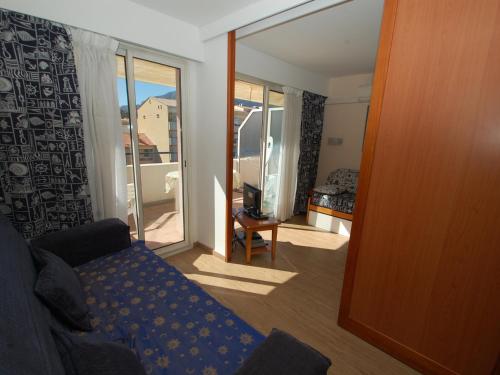 un salon avec un canapé et une porte coulissante en verre dans l'établissement Studio climatisé avec terrasse, parking et alcôve – Centre de Menton, proche plages et commerces - FR-1-196-191, à Menton