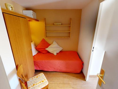 - une petite chambre avec un lit rouge dans l'établissement Studio climatisé avec terrasse, parking et alcôve – Centre de Menton, proche plages et commerces - FR-1-196-191, à Menton