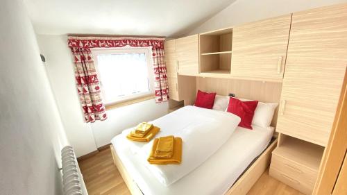 a small bedroom with a white bed with red pillows at Ciasa Coderoppola in Moena