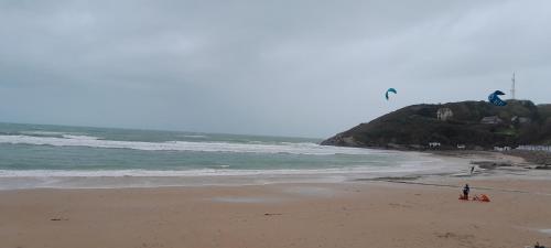 a person is flying a kite on the beach at Ecrin de tranquillité - Centre Village in Barneville-Carteret