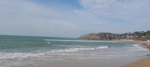 a beach with the ocean and some waves at Ecrin de tranquillité - Centre Village in Barneville-Carteret