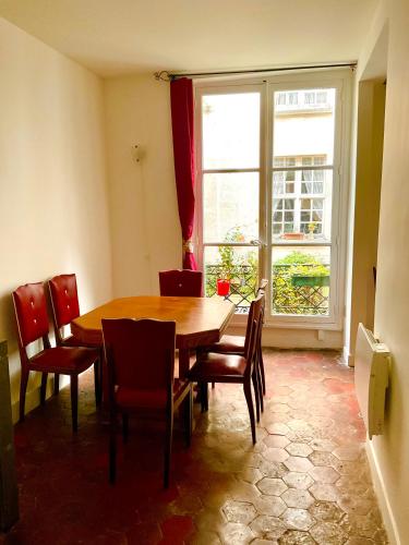 une salle à manger avec une table et des chaises et une fenêtre dans l'établissement Bel appartement ancien sur cour verdoyante, à Paris