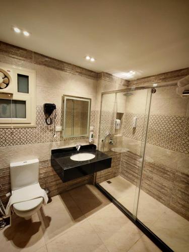 a bathroom with a toilet and a sink and a shower at Kush Hotel, Grand Museum & Pyramids View in Cairo