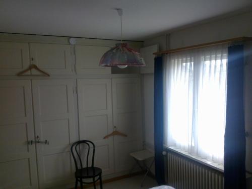 a room with a window and a chair and a lamp at Private Room on second floor with a View in Lenzburg