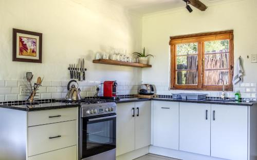 a kitchen with white cabinets and a stove top oven at Forest Valley Cottages in Knysna