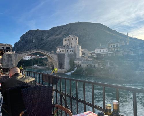 a man sitting in a chair in front of a bridge at Villa Anja Apartments in Mostar