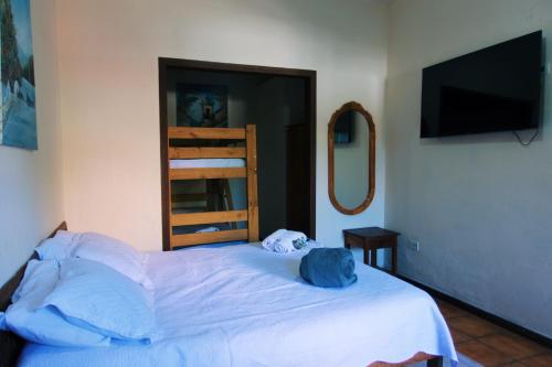 a bedroom with a white bed with a tv on the wall at POUSO DE ICARO - POUSADA NO CENTRO de PARATY in Paraty