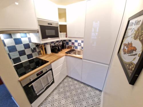 a small kitchen with white cabinets and a sink at Charming Apartment near Kings Cross in London