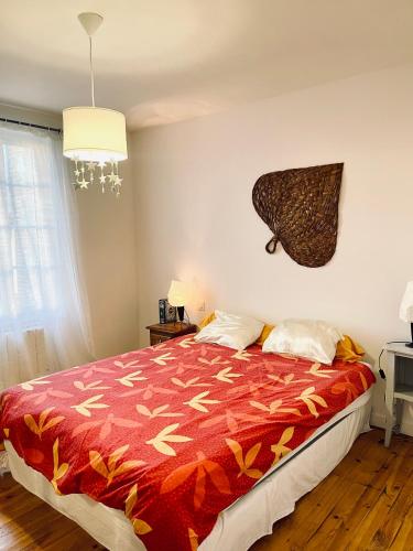 a bedroom with a bed with a red blanket at Le pont Saint Roch Logement lumineux avec garage in Lavaur