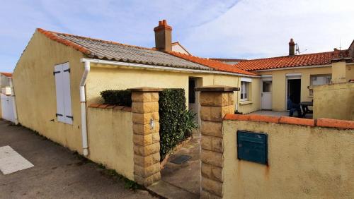a house with a brick wall and a gate at Maison de pêcheur in Brem-Sur-Mer