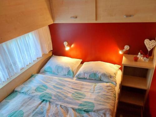 a bed in a room with a red wall at Hiška La Vita Kamp Terme 3000 Moravske Toplice vključeno 3x KOLO Športni rekviziti, Igrače in Moravske Toplice