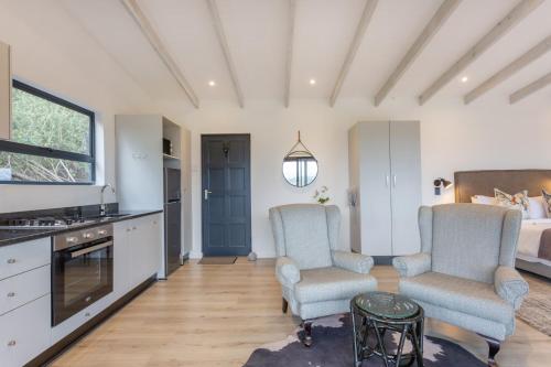 two chairs in a room with a kitchen and a bed at Forest Valley Cottages in Knysna