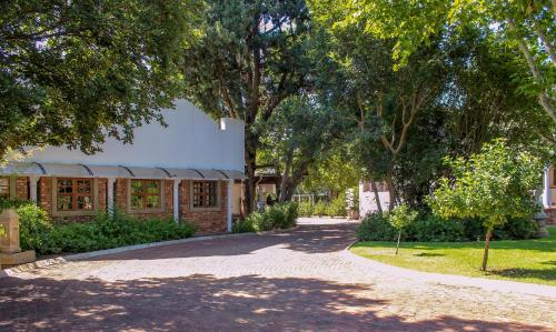 a driveway leading to a building with trees at The Fountain Villa in Klerksdorp