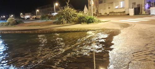a stream of water on a street at night at Ecrin de tranquillité - Centre Village in Barneville-Carteret