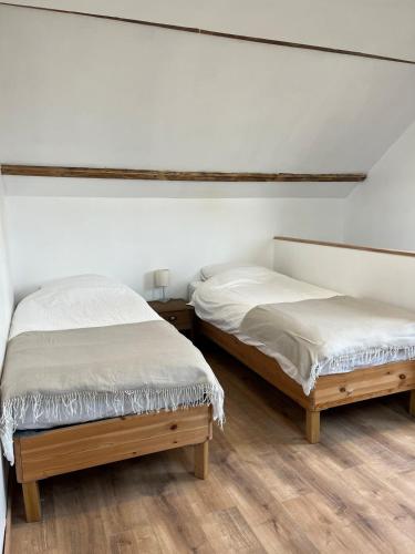 deux lits dans une chambre aux murs blancs et au parquet dans l'établissement Les Galets 2, à Auchonvillers