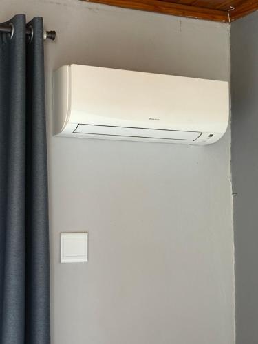 a white air conditioner in a room with a curtain at Blue Lotus Guest House Pta East-Solar power in Pretoria