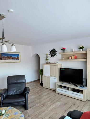 a living room with a television and a leather chair at Ferienwohnung Jansen in Kirchhundem