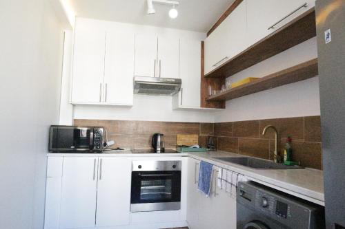 a kitchen with white cabinets and a sink and a dishwasher at senator park in Cape Town
