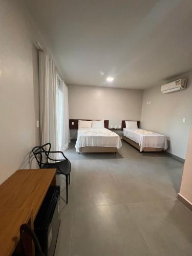 a hotel room with two beds and a table and chairs at Pousada Ilha do Desejo in Olivença