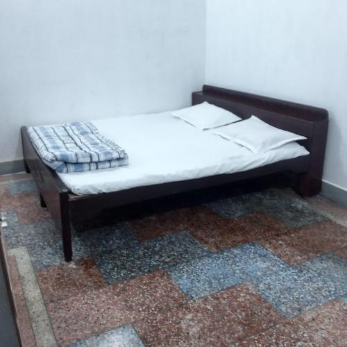 a bed with white sheets and a blanket on it at Shree Dhaam Homestay in Faizābād