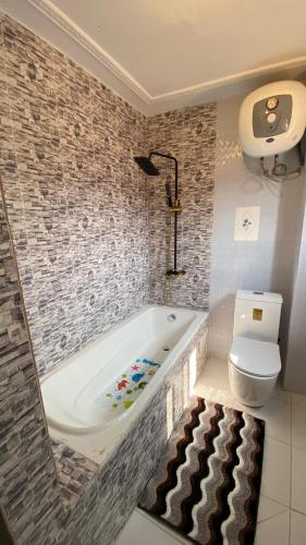 a bathroom with a bath tub and a toilet at Résidence hôtelière MEDOM Palace, Bastos in Yaoundé