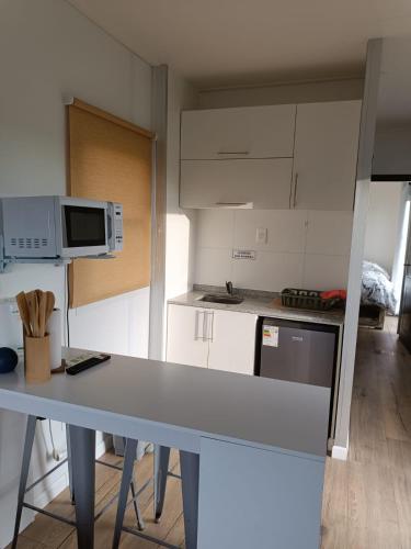 a white kitchen with a table and a microwave at La Martinna 2 in Trinidad