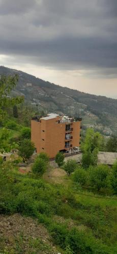 a large building in the middle of a field at SUKOON I Vacations I Conference I MICE I Family Events I Open Air Terrace I Sky Bonfire I Wooden Rooms With Pvt Balconies I Charvi Retreat by Exotic Stays in Kūfrī