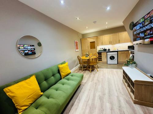 a living room with a green couch and a kitchen at Modern Living City Centre Spacious Apartments in Hull
