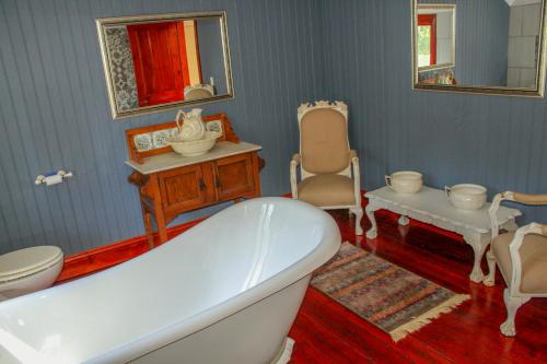 a bathroom with a tub and a chair and a sink at The Fountain Villa in Klerksdorp