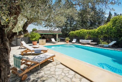 - une piscine bordée de chaises et d'un arbre dans l'établissement Mas des Olivades - Ferme Provençale - Piscine, à Pernes-les-Fontaines