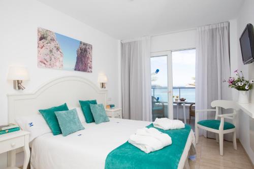 a bedroom with a white bed with green pillows at Hotel Marina in Port de Soller