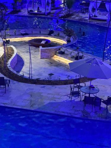 a swimming pool with a table and an umbrella at MALIA MURO ALTO STUDIO 300m DO MAR in Porto De Galinhas