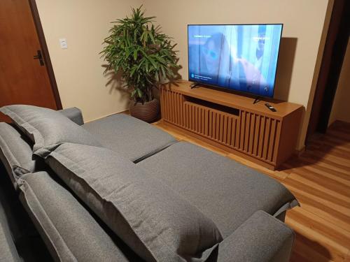 a living room with a couch and a flat screen tv at Meu canto em Lumiar in Nova Friburgo