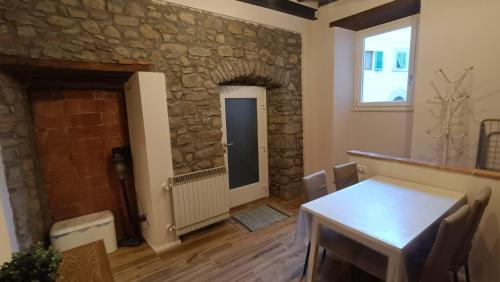 a dining room with a table and a stone wall at Kiki casina Piazza Lori in San Marcello Pistoiese