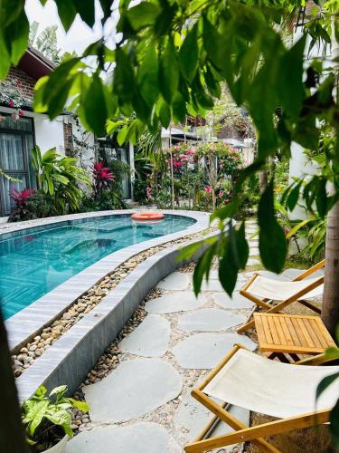 a swimming pool in a yard with chairs and trees at Tam Coc Boutique Garden in Ninh Binh
