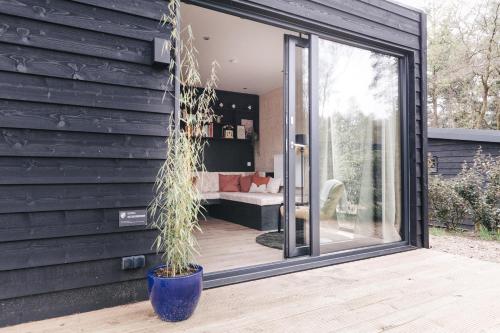 a glass extension to a house with a potted plant at Ultiem ontspannen in luxe en design ingericht tiny house in bosrijke omgeving in Nunspeet