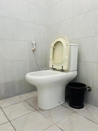 a white toilet with the seat up in a bathroom at The Luxe Apartment in Zanzibar City