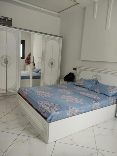 a white bedroom with a bed with a mirror at شقة مغربية تقليدية في وسط المدينة in Ksar el Kebir