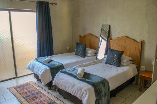 a bedroom with two beds and a window at The Fountain Villa in Klerksdorp