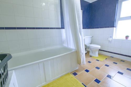 a bathroom with a bath tub and a toilet at Family house in Farnborough in Farnborough