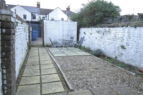 a patio with a table and chairs next to a brick wall at Family house in Farnborough in Farnborough