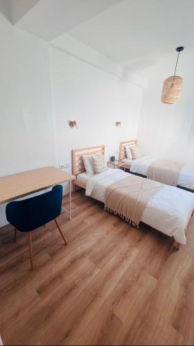 a room with two beds and a desk and a table at Villa Bleue Agadir climatisée-centre-3chambres in Agadir