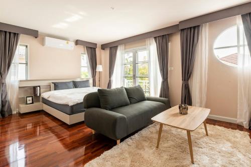a bedroom with a bed and a couch and a table at Top family house in peaceful area with lake view 3BR 15 mins to city in Chiang Mai
