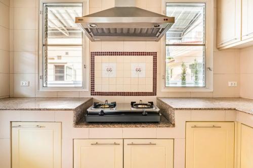 a kitchen with a stove top oven next to two windows at Top family house in peaceful area with lake view 3BR 15 mins to city in Chiang Mai