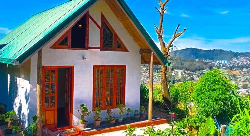 a small house with red doors on a hill at The Mount Lodge in Nuwara Eliya
