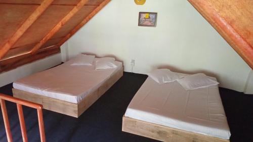 two beds in a room with wooden ceilings at The Mount Lodge in Nuwara Eliya
