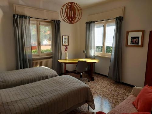 a bedroom with two beds and a table and a window at Villa dei Pini in Laveno-Mombello