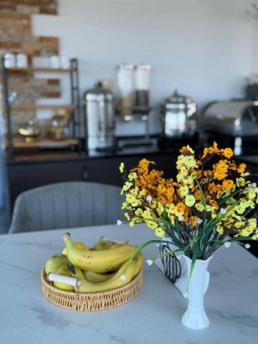 a table with a bowl of bananas and a vase of flowers at Black Sea Star Batumi in Batumi