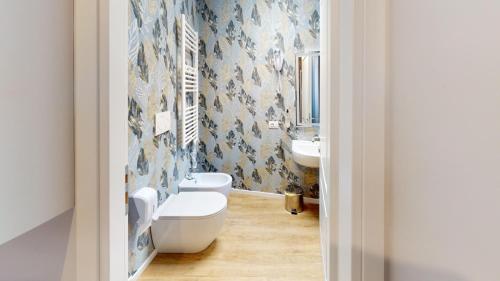 a bathroom with a toilet and a sink with blue wallpaper at ROME'S GLORIA HOTEL in Rome