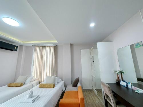 a room with two beds and a table and a desk at Daddy Dream Hotel and Residence in Ranong